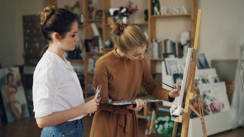 Two young women immersed in painting at an art studio with creative ambiance.