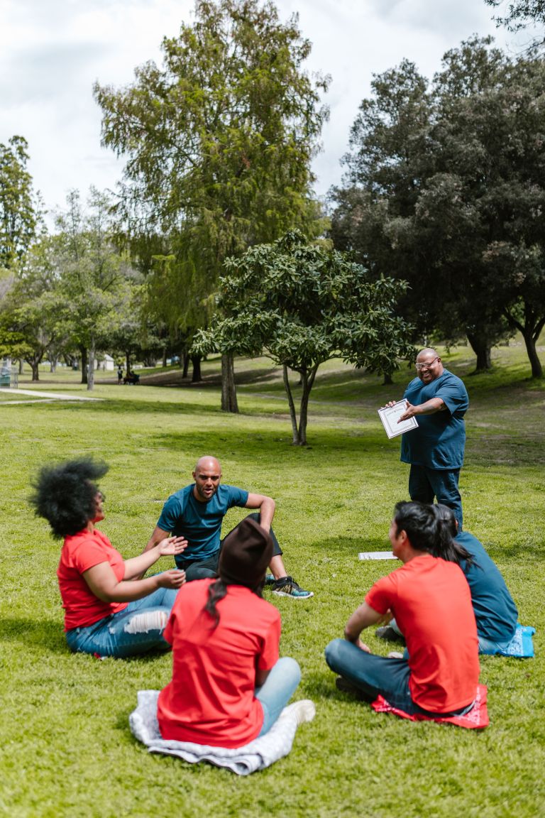 Group of adults enjoying a team building exercise in a sunny park setting.