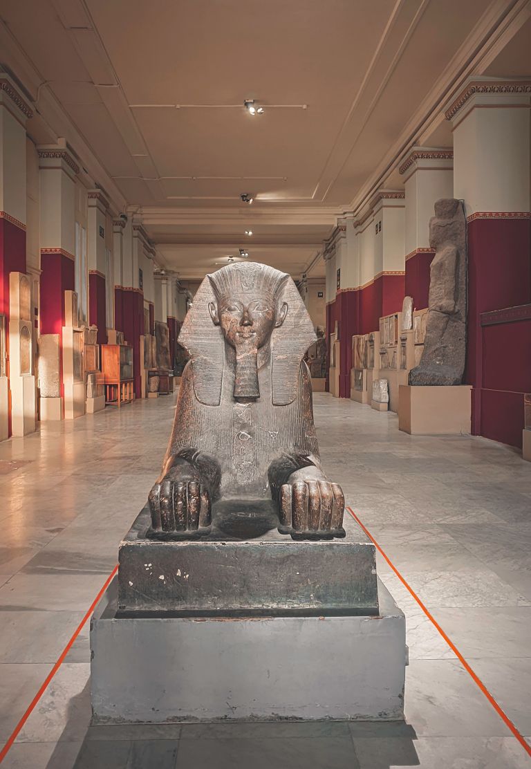 A detailed view of a Sphinx statue exhibited in an Egyptian museum hallway.